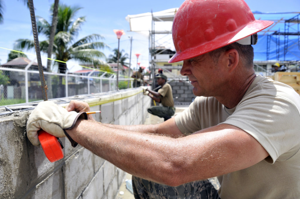 operário agachado medindo uma parede sendo construída medição de obras